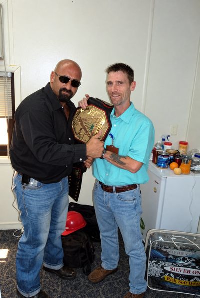 Holding a championship wrestling belt with Ali Farhat.